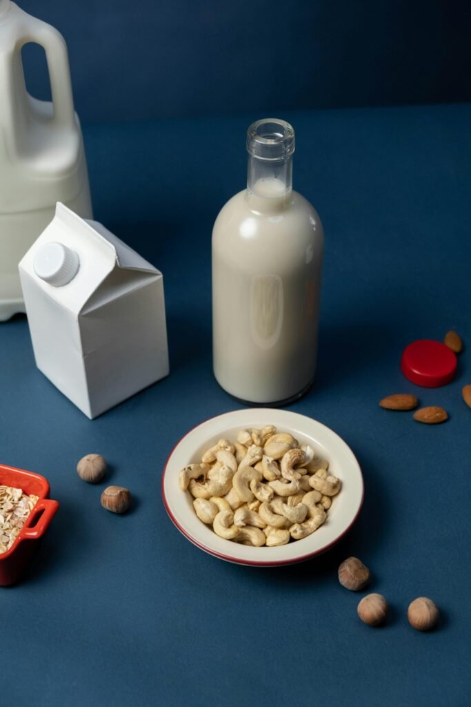 High-angle shot of nut milk and assorted nuts on a stylish blue surface.